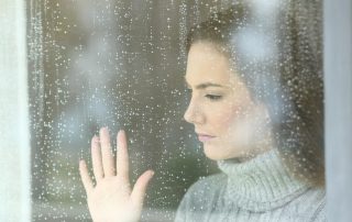 Woman looking through window (The Problems with Cheap Window Replacements)
